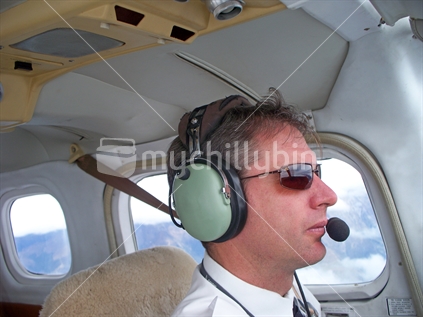 Pilot at controls of a light aircraft in flight over the South Island, New Zealand.