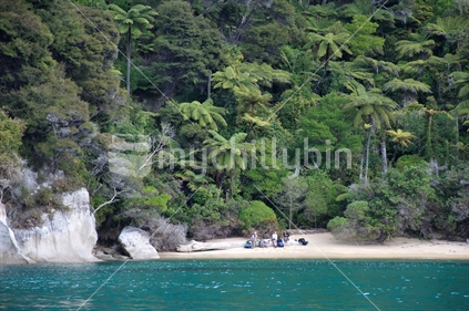 Trampers take a rest on a beach at Abel Tasman National Park, South Island