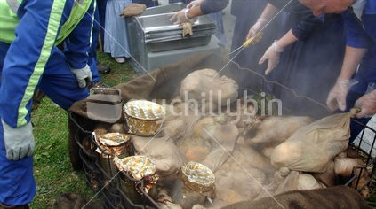 people unwrapping food cooked in a hangi