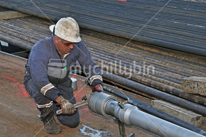 Drilling crewman tightens the cap on charges for perforating an oil well on the West Coast. Perforation allows crude from the oi-bearing strata to enter the well for pumping out.