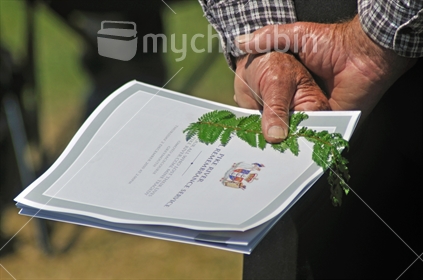Man holding silver fern and programme at the 2010 Memorial Service for 29 coal miners killed in the Pike River coal mine near Greymouth, West Coast.