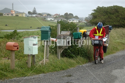 Postal worker on bicycle delivers mail for West Coast farmers, South Island