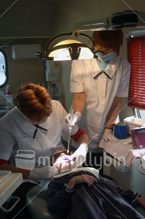 School dental nurses at work on a girl's tooth. Free dental care is provided for all children in New Zealand. On the West Coast the nurses work in a portable dental surgery.