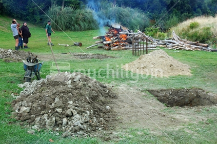 Fire burns over the top of the hole for a hangi, or Maori earth oven, for Waitangi Day celebrations, Greymouth, West Coast