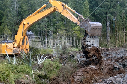 Excavator digging drainage channels through a wetland