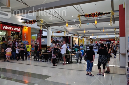 People shopping inside a New Zealand shopping mall, with Christmas decorations.