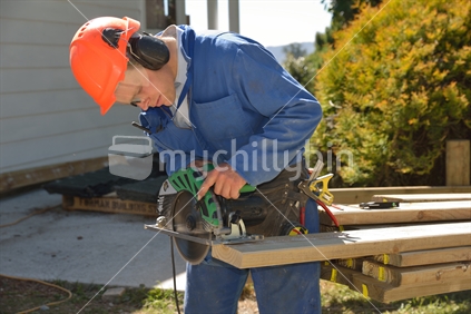 A builder measures his piece of timber for a fence around the house