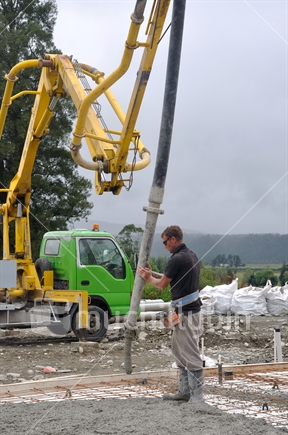 Builder uses a concrete pump to direct wet concrete into the foundations of a large building near Greymouth, South Island
