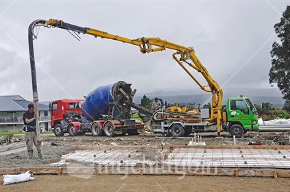 Builders use a concrete pump to direct wet cement into the foundations of a large building near Greymouth, South Island, New Zealand.