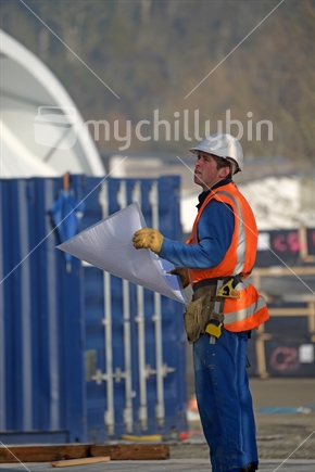 A builder consults his plans at the construction site