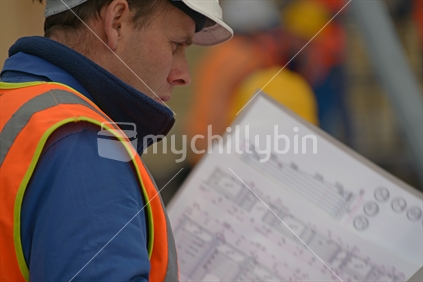 A builder consults his plans at the construction site
