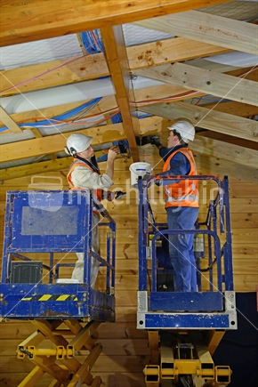 Tradesman painting the beams inside a wooden industrial building with another layer of clear coat