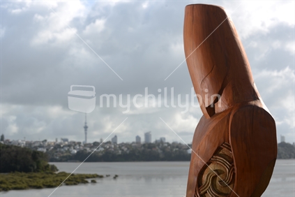 A carving of a Maori pou or guardian overlooks the Orakei Basin in Auckland where a Maori village once stood