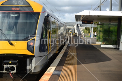 A commuter train waits for passengers at a suburban Auckland train station