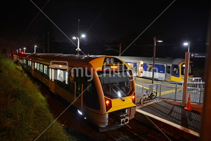 A commuter train waits for passengers at a suburban Auckland train station