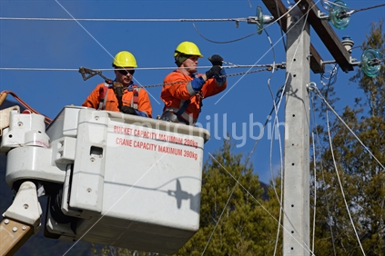 A linesman wires up a mains power supply cable on a new pole