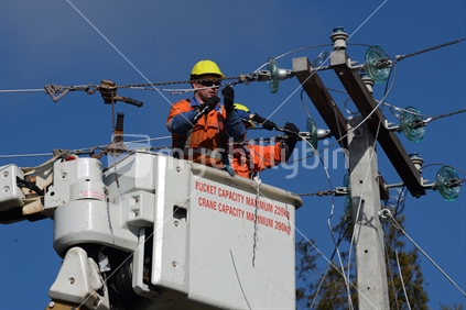 A linesman wires up a mains power supply cable on a new pole