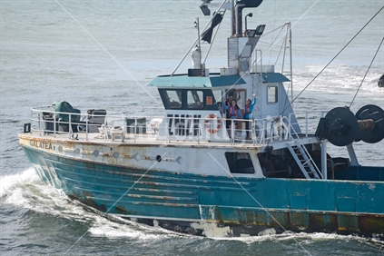 Passengers on the Galatea II wave while  crossing the bar of the Grey River on the West Coast. The Galatea II is a small steel hull stern trawler with a gross weight of 156 ton.