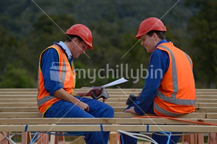 Two electricians discuss the plan for a major construction job