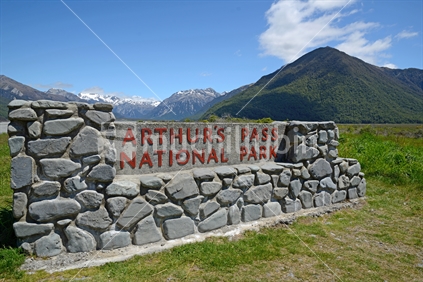 A rock wall sign for the Arthurs Pass National Park near the Bealey Bridge and the Waimakariri River in Canterbury, New Zealand