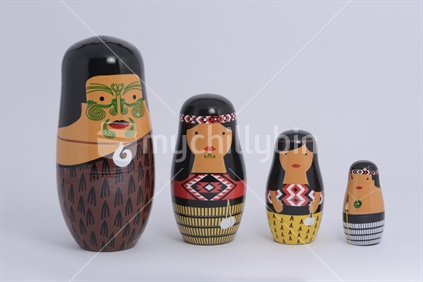 Blended cultures; a family of wooden Maori dolls styled as traditional Russian dolls on a white background