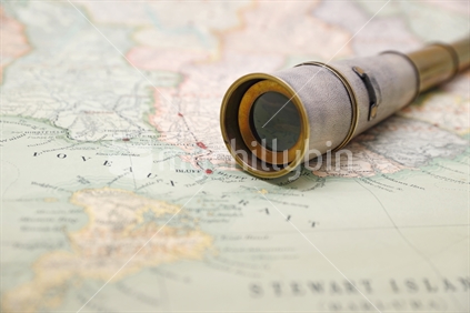 Antique brass telescope on a map of New Zealand