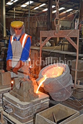 Foundrymen pour molten iron into moulds for making fire grates