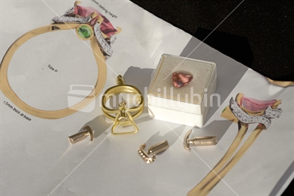 Components of a cast gold ring and a semi-precious stone laid out on the catalogue page