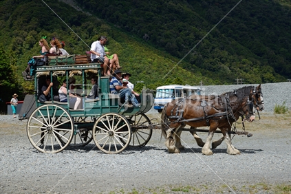 A pair of Clydesdales pull a stagecoach into the Otira Stagecoach Hotel