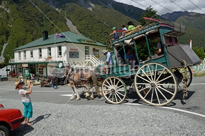 A pair of Clydesdales horses pull a stagecoach of passengers near the Otira hotel, West Coast