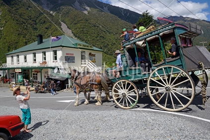 A pair of Clydesdales horses pull a stagecoach of passengers near the Otira hotel, West Coast