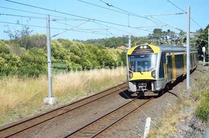 A commuter train departs from a suburban Auckland train station