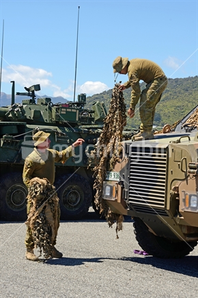 GREYMOUTH, NEW ZEALAND, NOVEMBER 18, 2017: The crew of a personnel carrier wrap up camouflage netting and prepare to depart from Greymouth after an open day for the military.