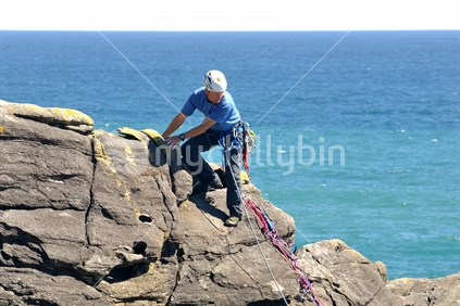 An unidentified adventurer climbs a cliff near Charleston on the West Coast.