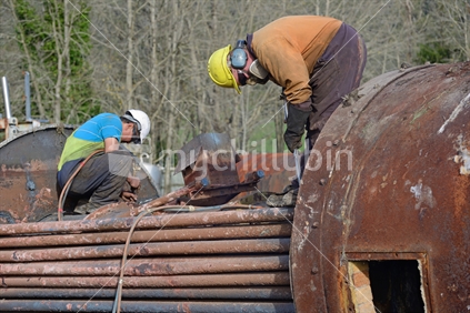 An engineer cuts up an old boiler for scrap metal