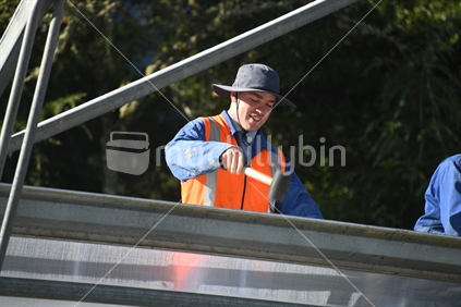 GREYMOUTH, NEW ZEALAND, DECEMBER 12, 2018: Tradesmen secure the plastic on a new tunnel house.