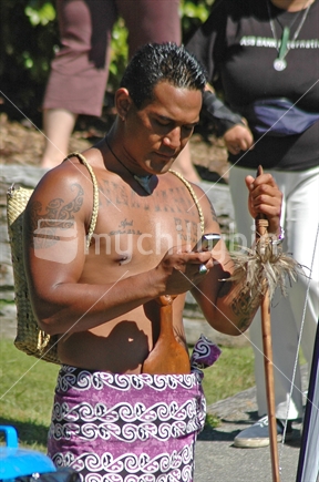 Waitangi Day warrior, using cell phone.