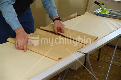 A man rolls up some glued wallpaper, ready to decorate a bedroom