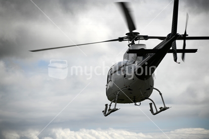 A large helicopter takes off into a cloudy sky