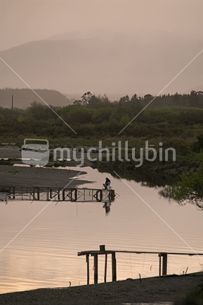 HOKITIKA, NEW ZEALAND, OCTOBER 5, 2019: A man awaits sunrise and the whitebait at his stand on the Hokitika River on the West Coast of the South Island