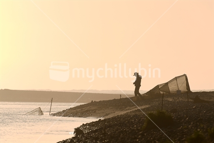 GREYMOUTH, NEW ZEALAND, SEPTEMBER 18 2019: A man works his whitebaiting stand at the mouth of the Taramakau River on the West Coast of the South Island