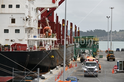 LYTTLETON, NEW ZEALAND, NOVEMBER 21, 2019: Trucks carry away cargo from the Powan (IMO: 9721578, MMSI 477027600)  a Bulk Carrier built in 2016 and currently sailing under the flag of Hong Kong, while docked at Lyttleton harbour..
