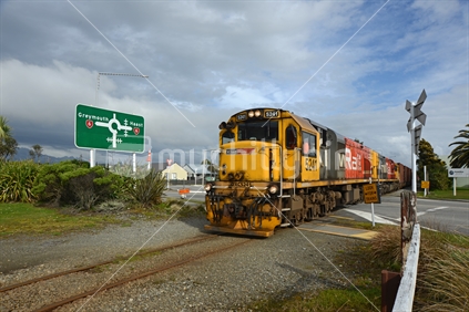 HOKITIKA, NEW ZEALAND, AUGUST 29, 2020: A freight train crosses the main street of Hokitika near the roundabout on State Highway 6.