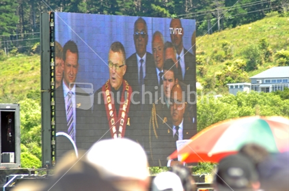 The Mayor of Greymouth, Tony Kokshoorn appears on the big screen while speaking at the 2010 Memorial Service for 29 coal miners killed in the Pike River coal mine near Greymouth, West Coast