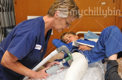 Nurse cuts the plaster off a boys broken leg, Greymouth Base hospital, Westland