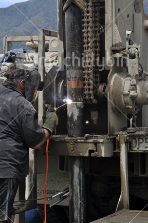 Man welding pipes for water well drilling operation