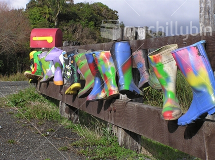 Painted gumboots nailed to fence.