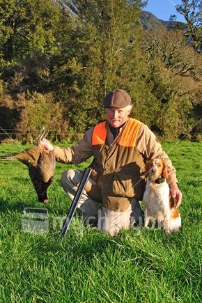 Successful pheasant hunter with his retriever on the West Coast, South Island, New Zealand