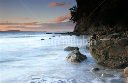 A rocky coastal beach at dusk.