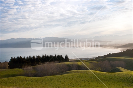 Patterned sky over mountains, coast and farmland